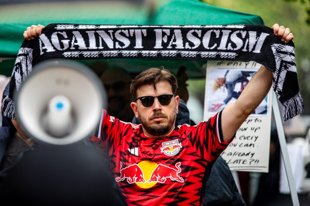 Man holds up scarf that reads Against Fascism